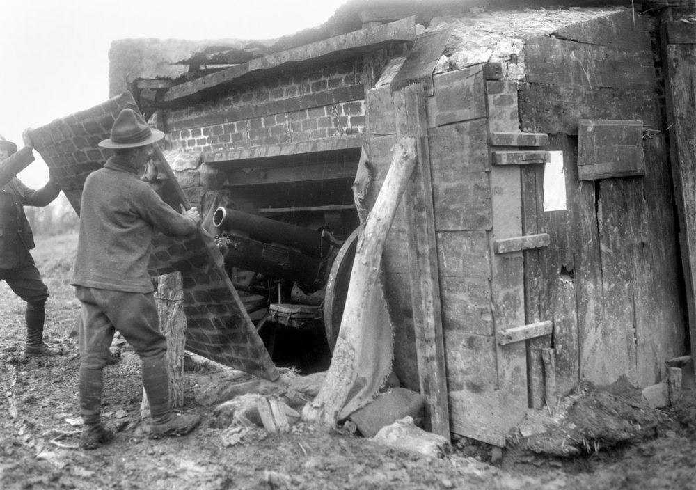 A New Zealand artilleryman removes a camouflage canvas screen from a concealed Howitzer emplacement. Messines, 4 March 1917.